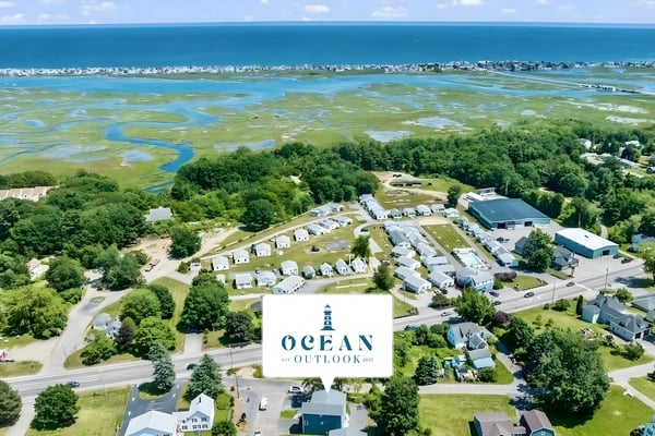 Aerial view of coastal community with homes, marshlands, and ocean beyond